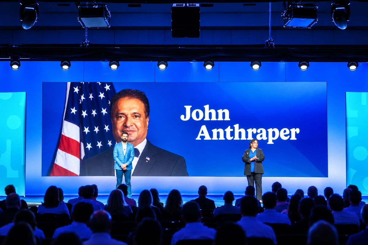 A tribute to John Anthraper displayed on stage before an audience