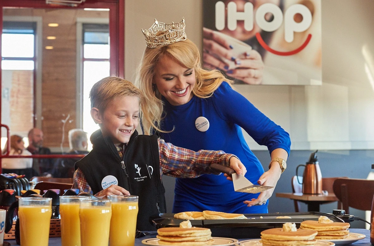 A National Pancake Day celebration at IHOP, with a child and a volunteer making pancakes together
